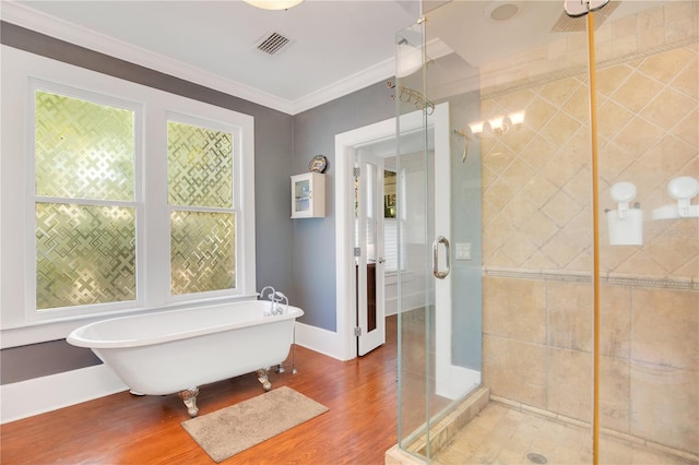 full bath featuring wood finished floors, visible vents, a freestanding tub, a shower stall, and crown molding