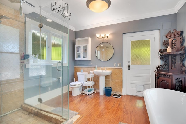 bathroom with a sink, wood finished floors, tile walls, a shower stall, and crown molding