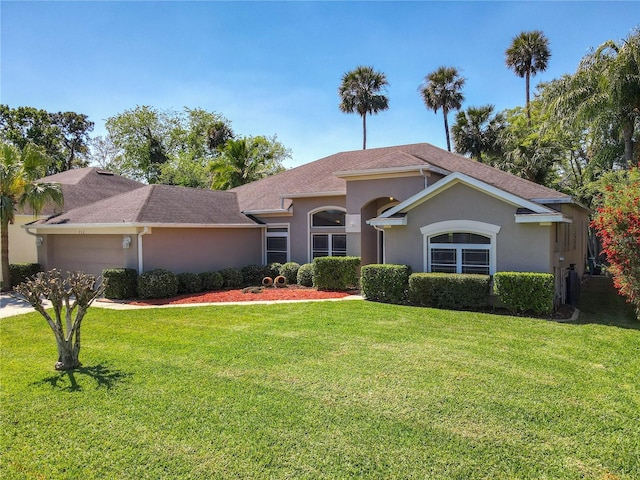 view of front of property with stucco siding, a front yard, a garage, and a shingled roof