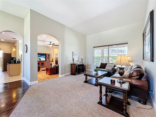 living room featuring arched walkways, a ceiling fan, and baseboards