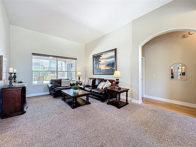 carpeted living room with baseboards and arched walkways