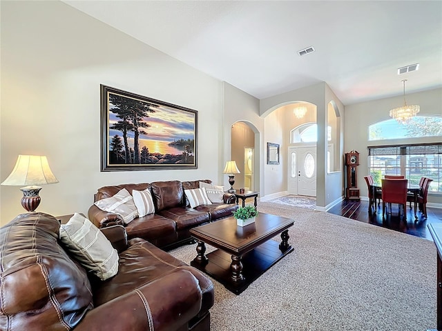 living room featuring wood finished floors, visible vents, arched walkways, and a chandelier