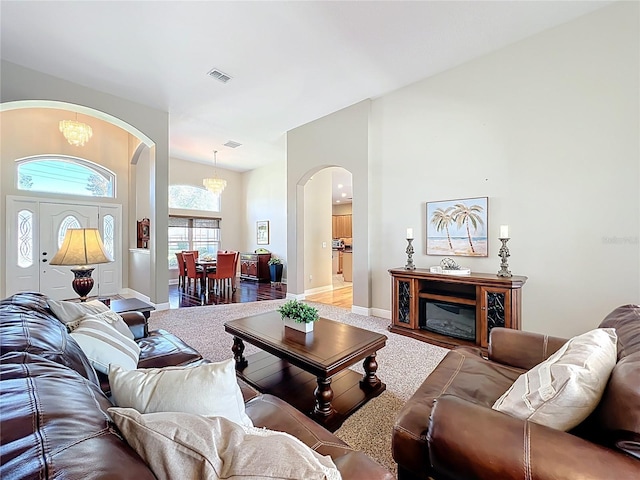 living room featuring arched walkways, a notable chandelier, visible vents, and baseboards