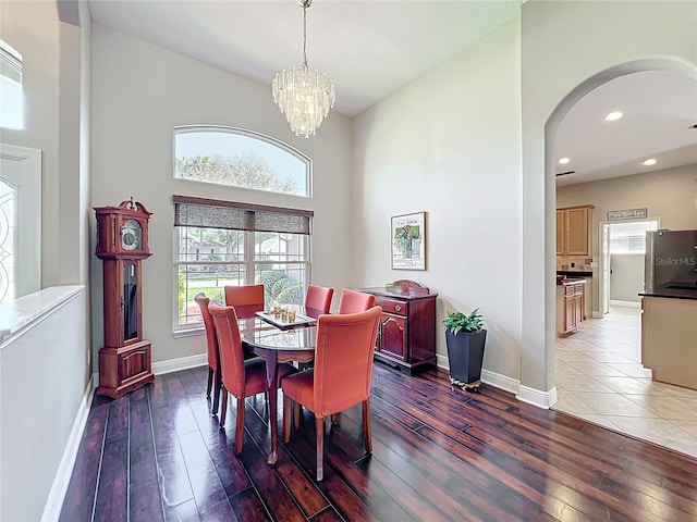 dining area featuring hardwood / wood-style flooring, baseboards, arched walkways, and a chandelier