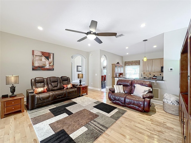 living room with visible vents, light wood-style flooring, recessed lighting, arched walkways, and ceiling fan