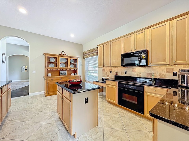 kitchen with a kitchen island, light tile patterned flooring, arched walkways, black appliances, and backsplash