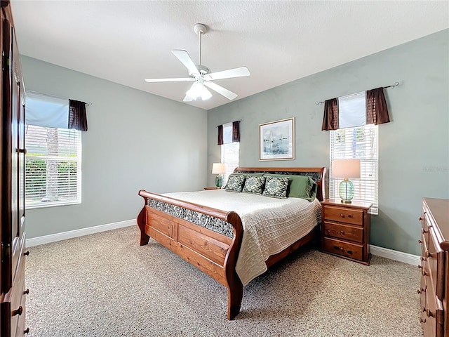 bedroom featuring baseboards, light colored carpet, a ceiling fan, and a textured ceiling