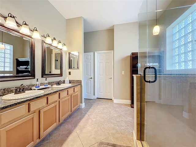 bathroom with a sink, a shower with door, double vanity, and tile patterned floors