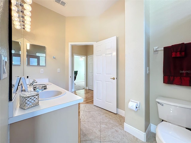 full bath with visible vents, baseboards, double vanity, a sink, and toilet