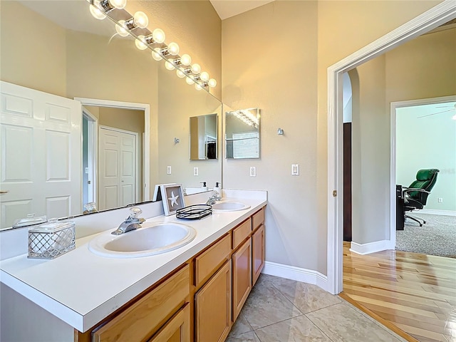 full bathroom featuring a sink, baseboards, and double vanity