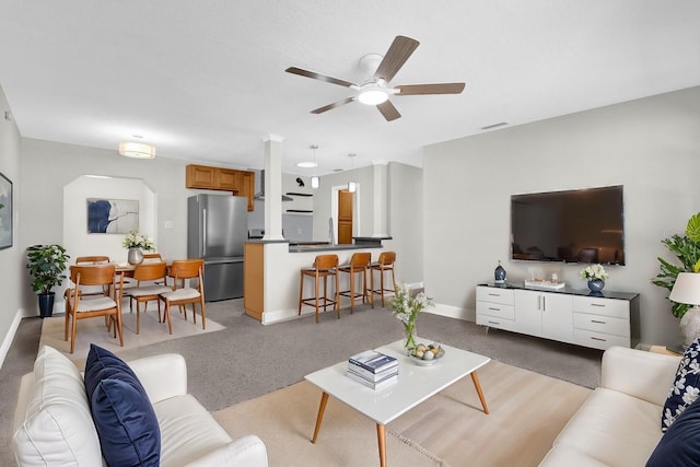 living area featuring visible vents, baseboards, light colored carpet, and ceiling fan