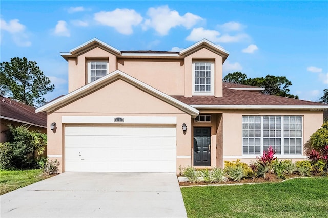 traditional-style home featuring stucco siding, driveway, a front yard, a shingled roof, and a garage