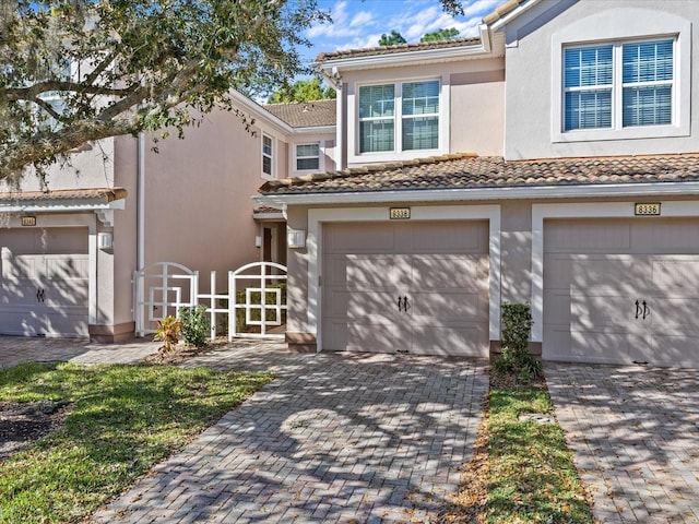 view of front of home with a tiled roof, stucco siding, driveway, and a garage