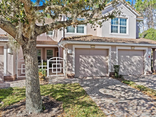 view of front of house with a tiled roof, decorative driveway, and stucco siding