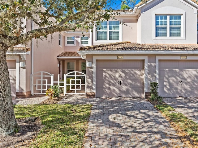 view of front facade featuring stucco siding, an attached garage, driveway, and a tile roof