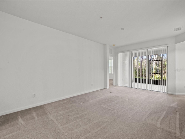 unfurnished room with light carpet, visible vents, and baseboards