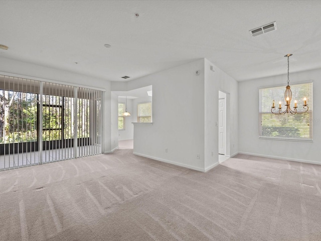 unfurnished room featuring visible vents, an inviting chandelier, baseboards, and carpet