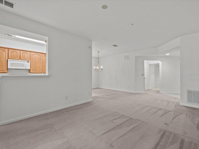 spare room with visible vents, light carpet, a notable chandelier, and baseboards