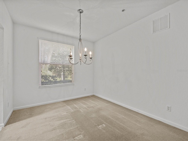 carpeted spare room with a notable chandelier, visible vents, and baseboards