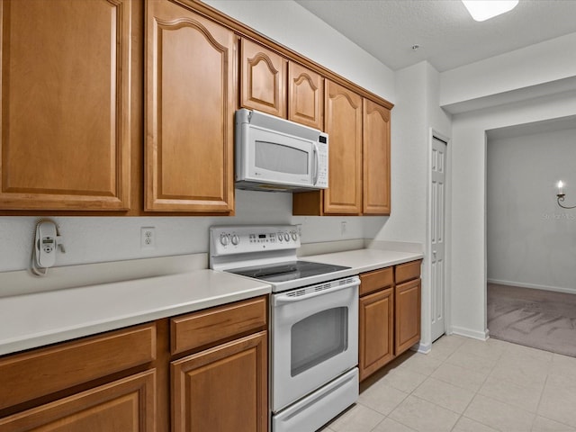 kitchen with white appliances, light countertops, brown cabinets, and baseboards