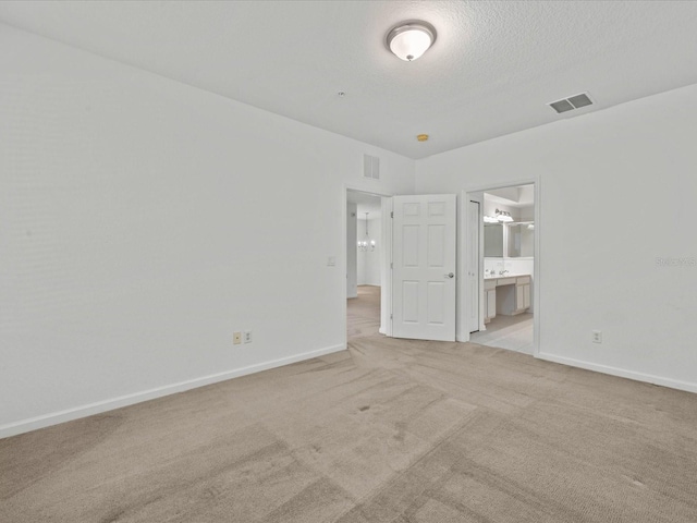 unfurnished bedroom featuring a textured ceiling, light colored carpet, visible vents, and baseboards