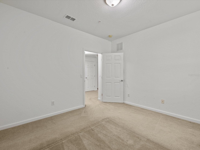 empty room with light colored carpet, visible vents, and baseboards