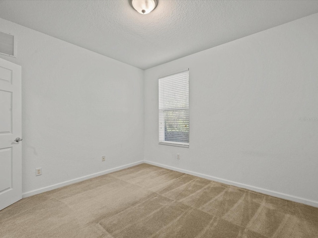 unfurnished room with visible vents, light carpet, a textured ceiling, and baseboards