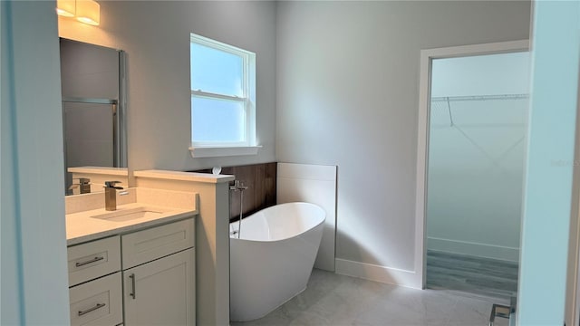 15369 SW 60th Cir, Ocala, FL 34473 - full bathroom featuring a freestanding bath, a walk in closet, vanity, marble look tiles, and baseboards