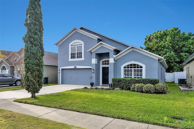 traditional-style house with fence, concrete driveway, a front yard, stucco siding, and a garage