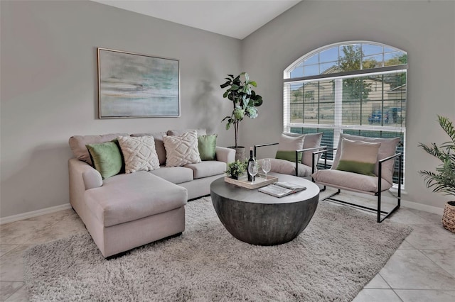 living room with tile patterned floors, baseboards, and vaulted ceiling