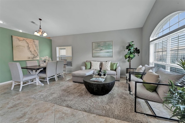 living room featuring a chandelier, visible vents, lofted ceiling, and baseboards