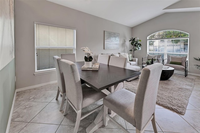 dining area featuring light tile patterned flooring, baseboards, and lofted ceiling