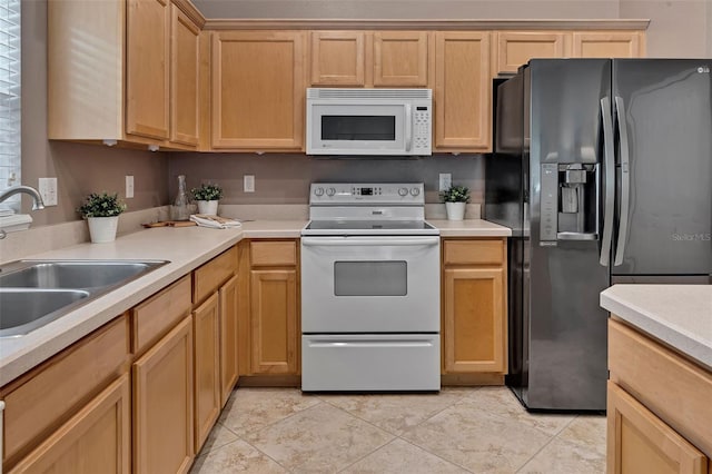 kitchen with white appliances, light tile patterned floors, light brown cabinetry, a sink, and light countertops