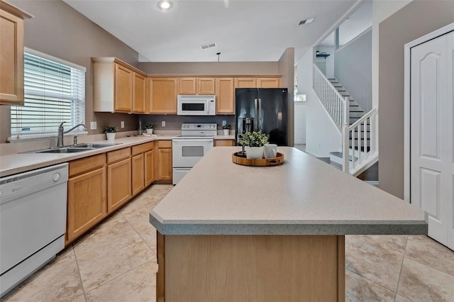 kitchen featuring white appliances, light brown cabinets, visible vents, a sink, and a center island