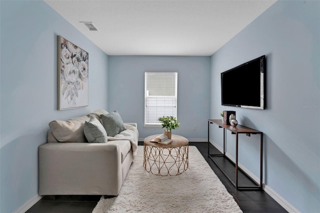 living room with visible vents, baseboards, and dark wood-style floors