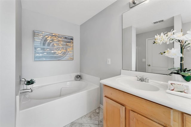 full bath with vanity, a garden tub, and visible vents