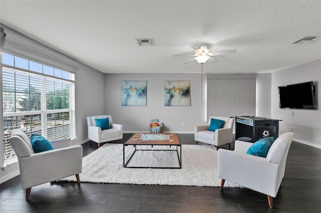 living room featuring visible vents, baseboards, a textured ceiling, and dark wood finished floors