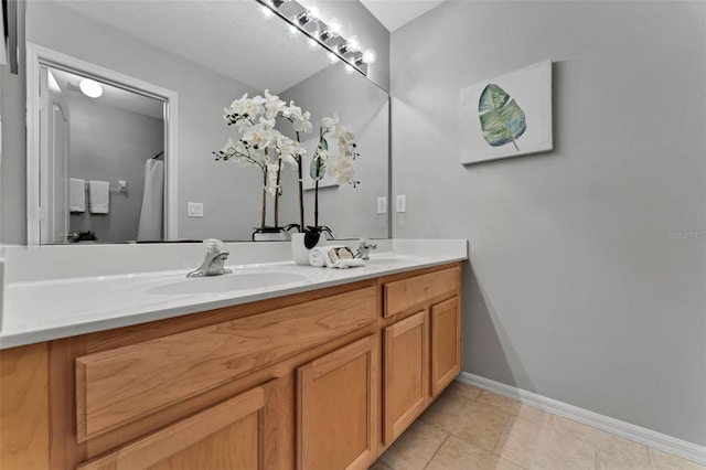 bathroom featuring double vanity, tile patterned floors, baseboards, and a sink