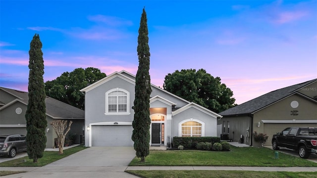 traditional-style house featuring stucco siding, driveway, a lawn, and a garage