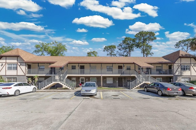 view of property featuring stairway and uncovered parking