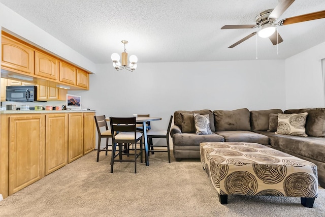 living area with ceiling fan with notable chandelier, light colored carpet, and a textured ceiling