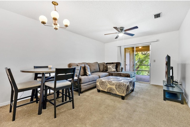 living area featuring visible vents, ceiling fan with notable chandelier, a textured ceiling, baseboards, and light colored carpet