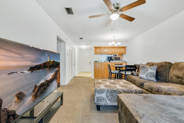 living room with visible vents, light colored carpet, and ceiling fan with notable chandelier