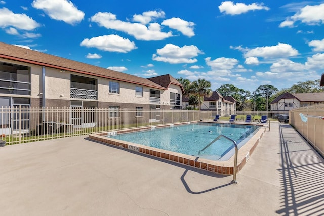 pool with a patio area and fence