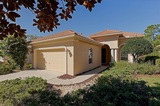 view of front facade with stucco siding, concrete driveway, a tile roof, and a garage