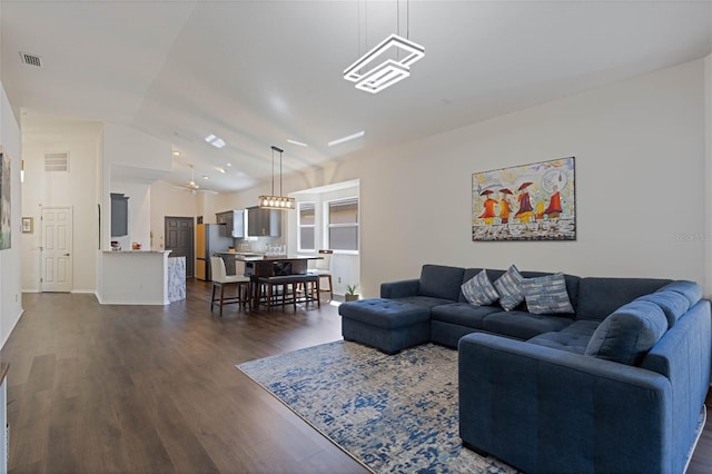 living area featuring visible vents, baseboards, dark wood finished floors, and vaulted ceiling