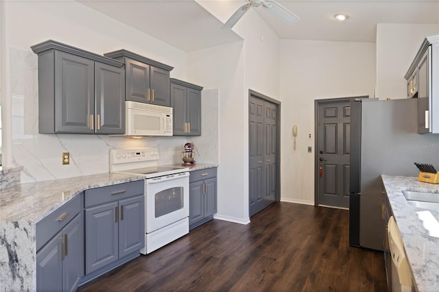 kitchen featuring white appliances, light stone countertops, dark wood-style flooring, ceiling fan, and tasteful backsplash