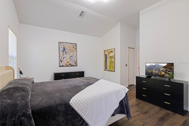 bedroom featuring vaulted ceiling, visible vents, and dark wood-style flooring