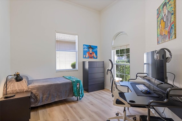 bedroom featuring wood finished floors and a towering ceiling