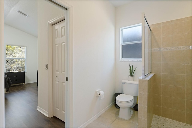 full bath with visible vents, tiled shower, toilet, and baseboards